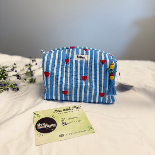 Blue striped pouch with heart patterns on a white surface, accompanied by a business card.