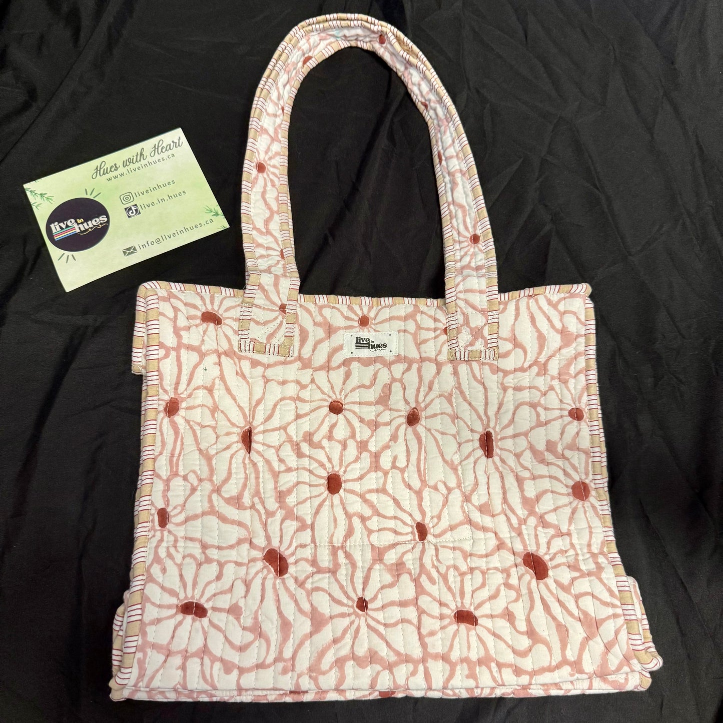 Floral patterned tote bag with a business card on a black background
