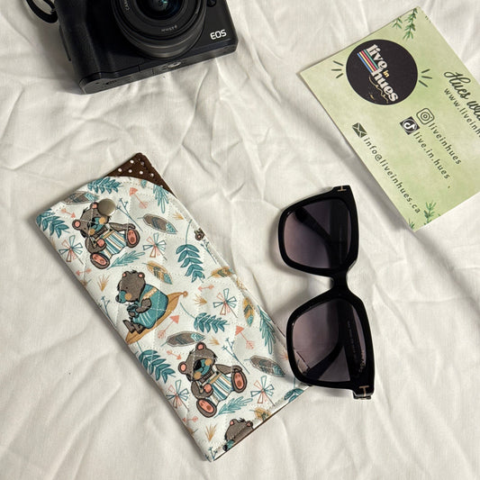 Camera, sunglasses, and patterned case on a white surface with 'live in hues' card.