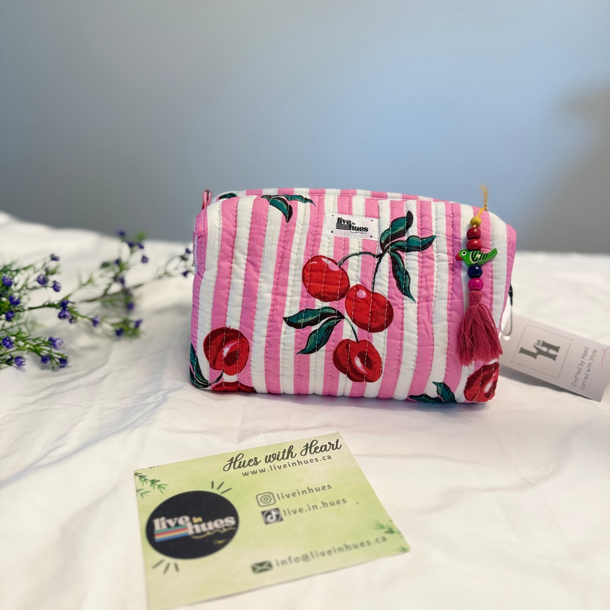 Pink striped pouch with cherry design on a white surface