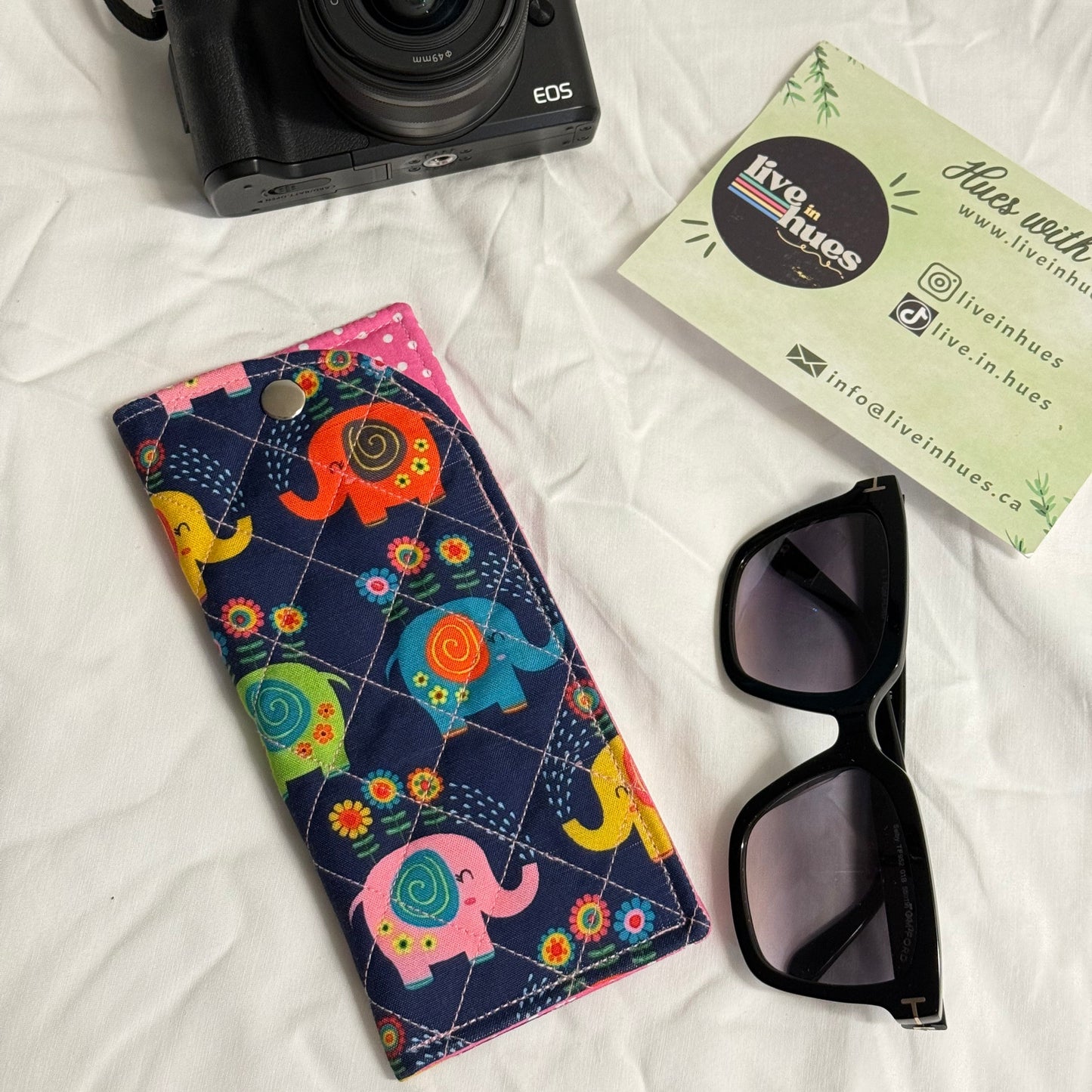 Camera, sunglasses, and colorful case on a white surface