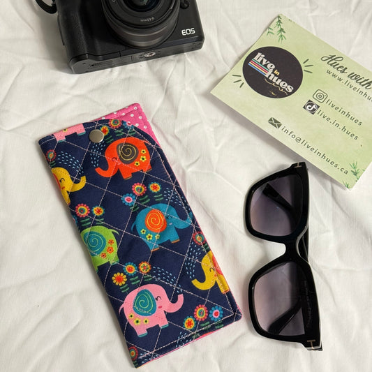 Camera, sunglasses, and colorful case on a white surface