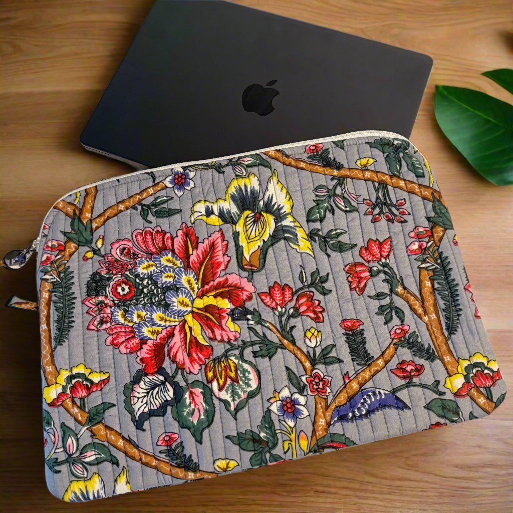 Floral and butterfly patterned pouch next to a black laptop on a white fabric background