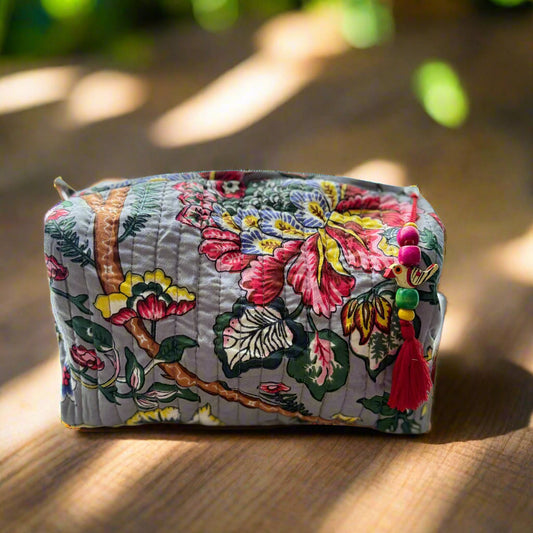 Floral-patterned box with colorful tassels on a beige background