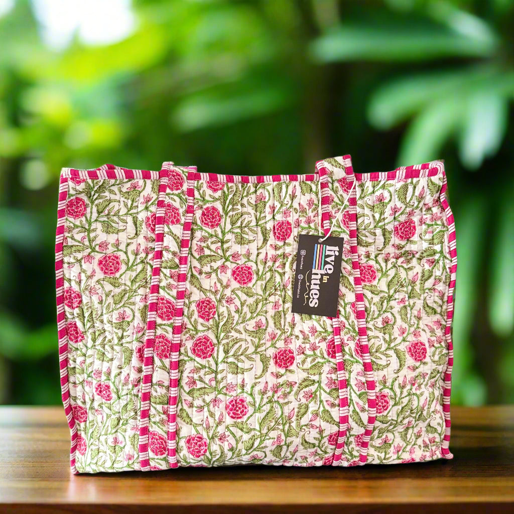 Stack of floral fabric placemats with a brand label on a gray background