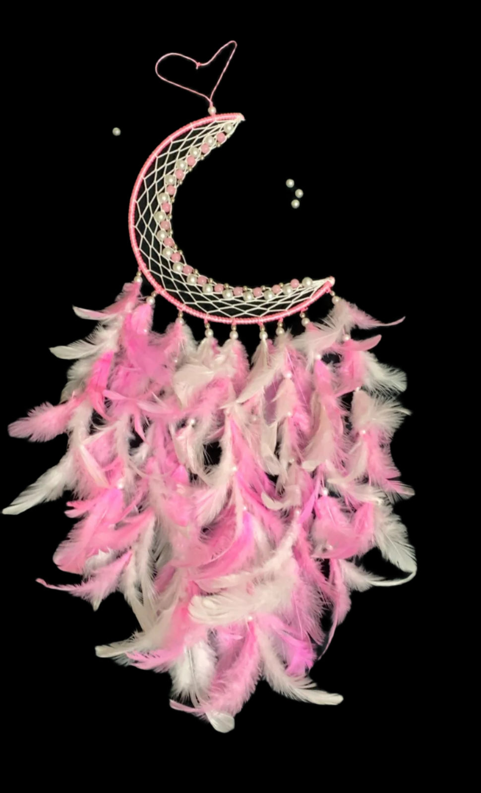 Pink and white feathered dreamcatcher with a crescent moon design on a black background