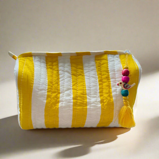 Yellow and white striped pouch with colorful tassels on a light background