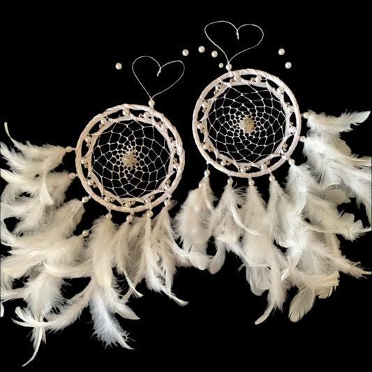 Two white feather dream catchers on a black background