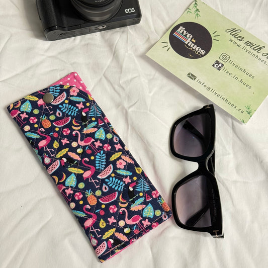 Camera, sunglasses, and patterned case on a white surface with visible brand name.