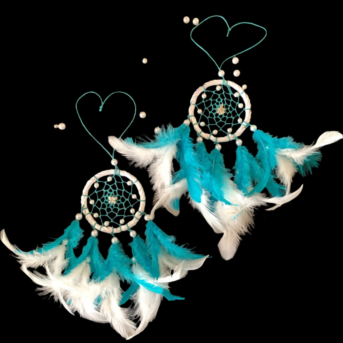 Pair of turquoise and white dreamcatcher earrings on a black background
