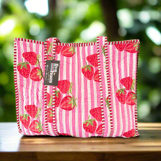 Pink striped bag with strawberry pattern on a gray surface