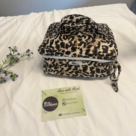 Leopard print bag on a white surface with a visible brand card.