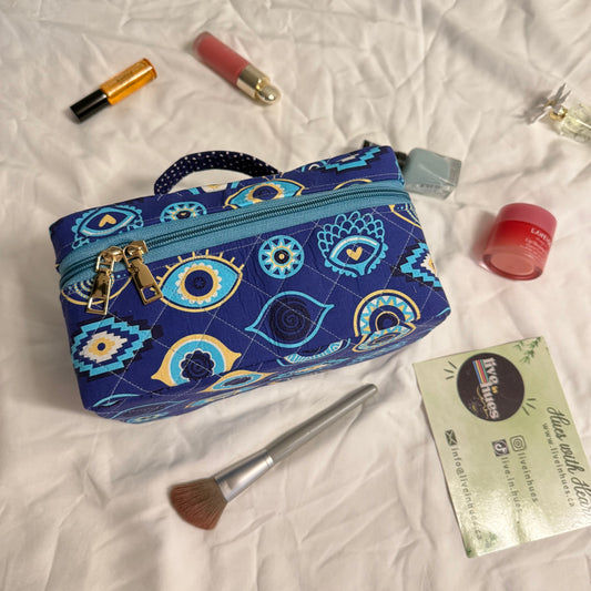 Blue patterned makeup bag with cosmetics on a white fabric background