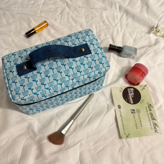 Blue patterned makeup bag with cosmetic items on a white textured surface