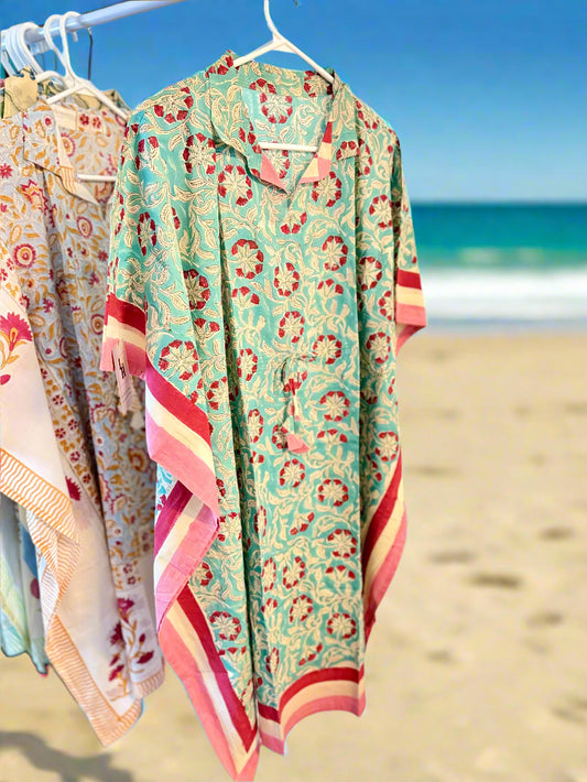 Colorful floral-patterned garment hanging on a rack against a white wall.