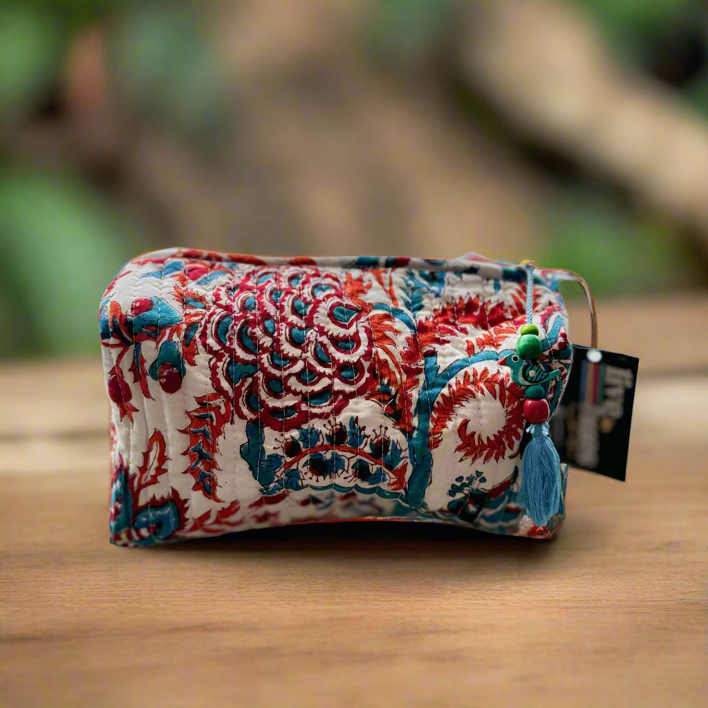 Decorative pouch with floral pattern on a textured surface with a blurred floral curtain background
