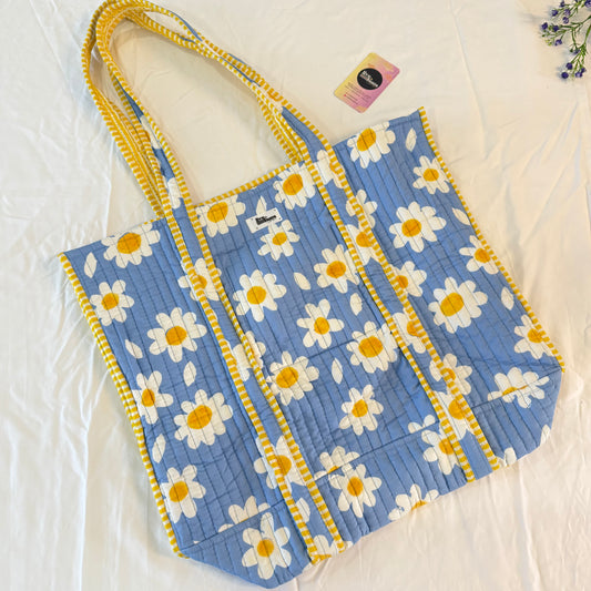 Blue tote bag with white daisy pattern on a white background
