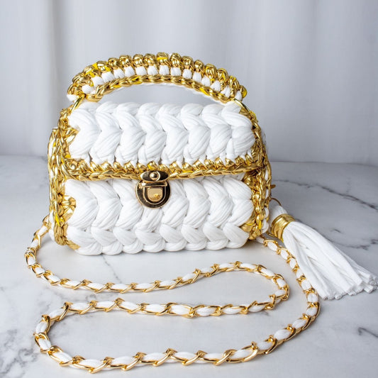 White handbag with gold chain and handle on a marble surface