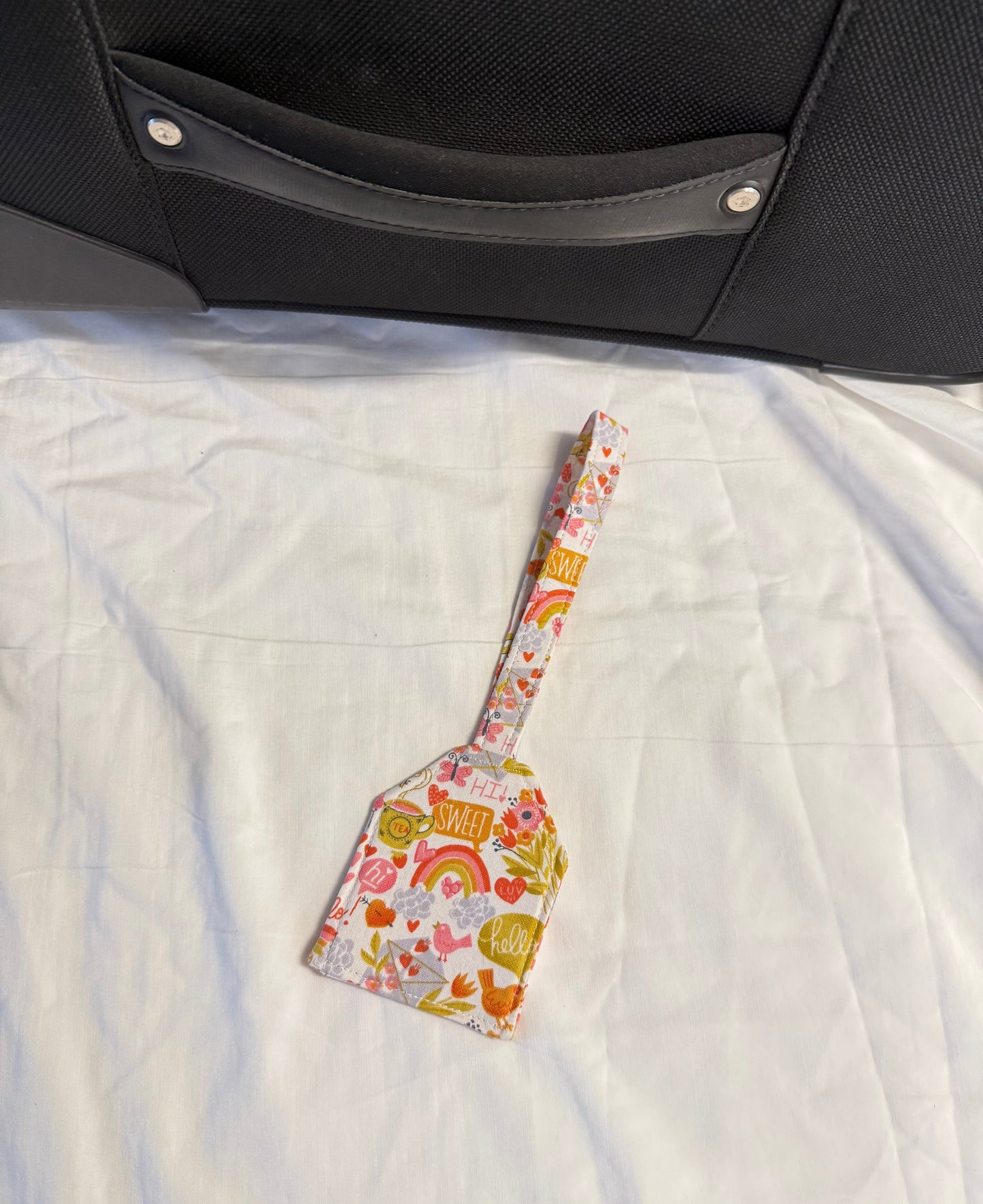 Floral-patterned spatula on a textured surface next to a suitcase