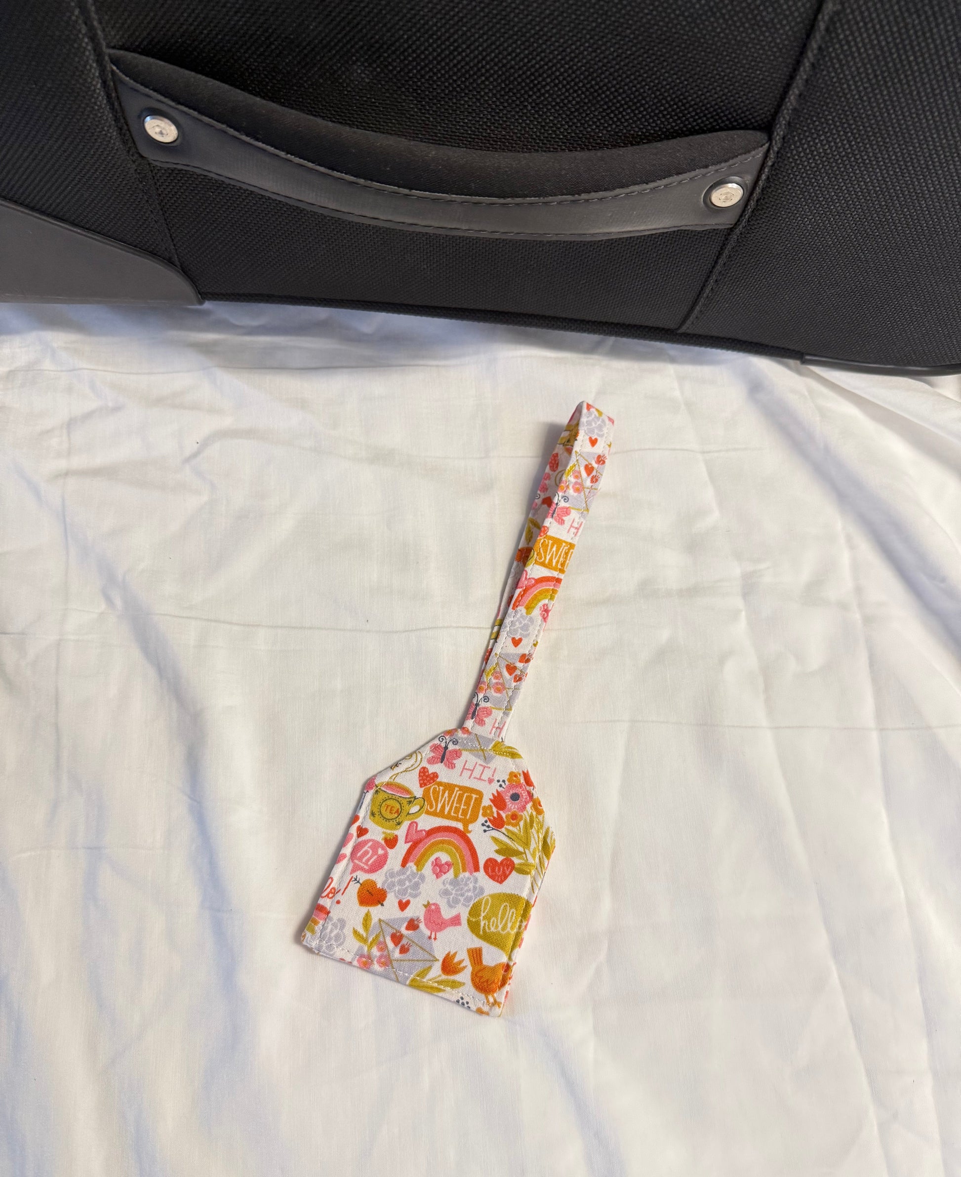 Floral-patterned spatula on a textured surface next to a suitcase