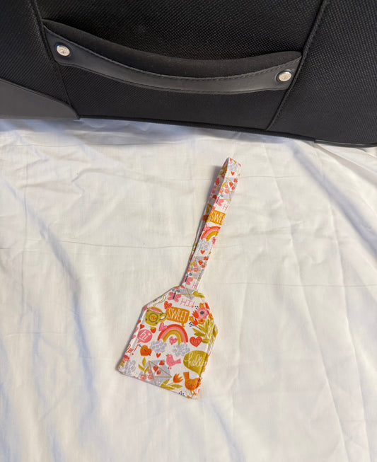 Floral-patterned spatula on a textured surface next to a suitcase
