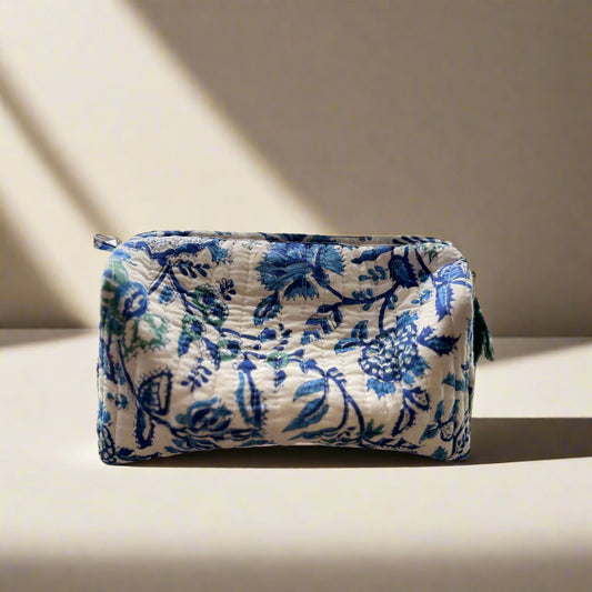 Blue floral-patterned pouch on a textured surface with a floral curtain in the background