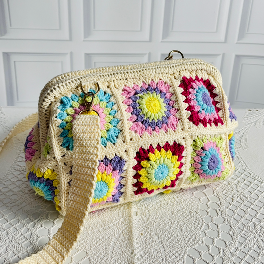 Colorful granny square bag on a textured surface with a white paneled wall in the background.