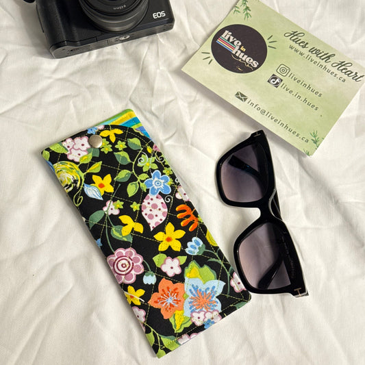 Camera, sunglasses, and floral case on a white surface