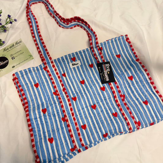 Blue and white striped bag with red hearts on a white background