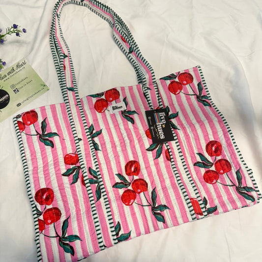 Pink and white striped bag with cherry design on a white surface