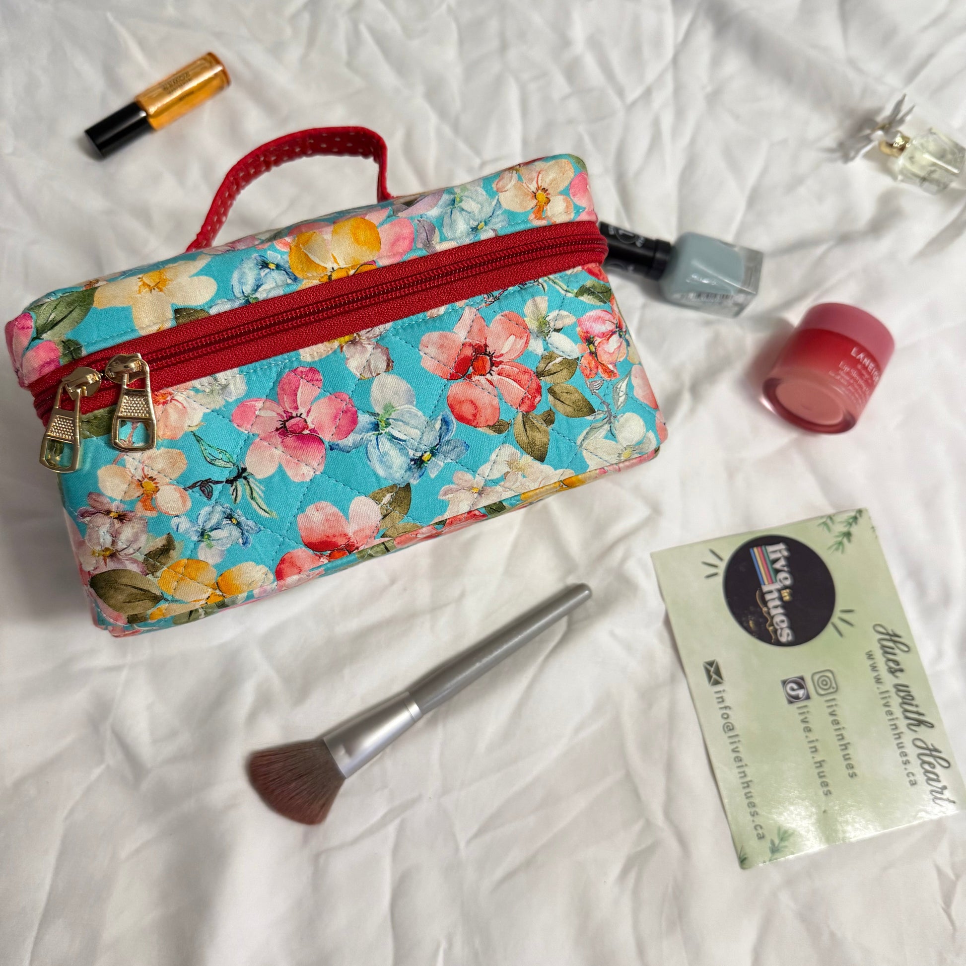 Floral makeup bag with cosmetic items on a white fabric background