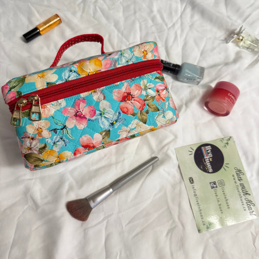 Floral makeup bag with cosmetic items on a white fabric background