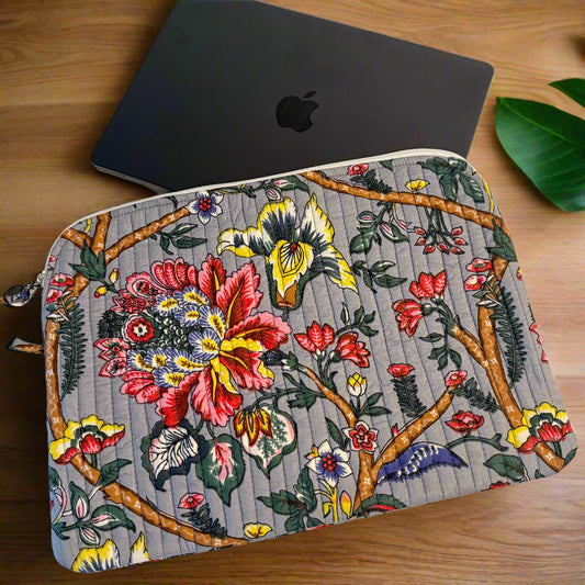 Floral and butterfly patterned pouch next to a black laptop on a white fabric background