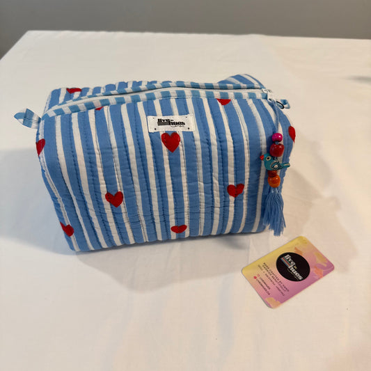 A blue and white striped fabric pouch with red heart prints, featuring a tassel charm and a small brand tag, displayed on a white surface next to its product card.