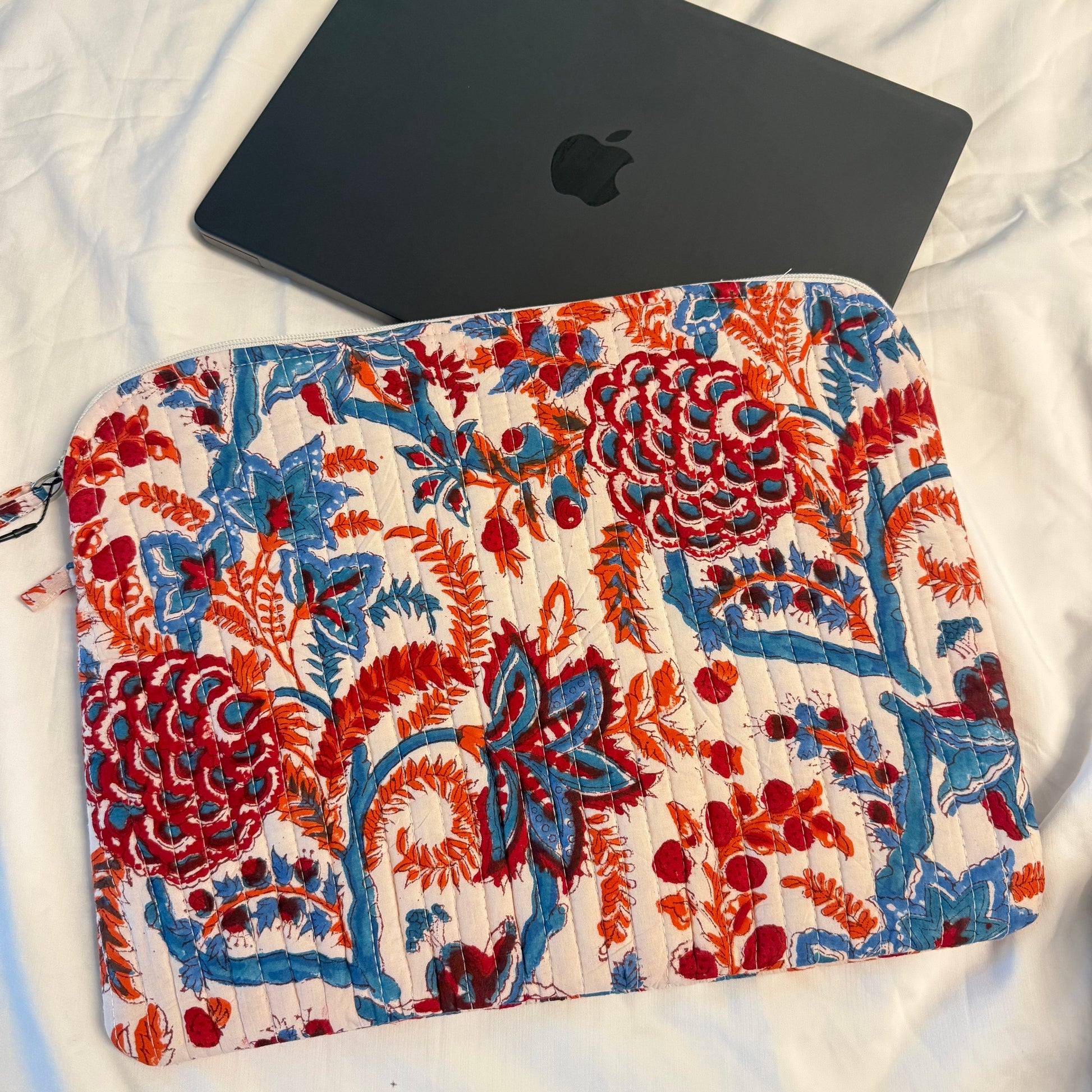Floral-patterned pouch next to a black laptop on a white surface