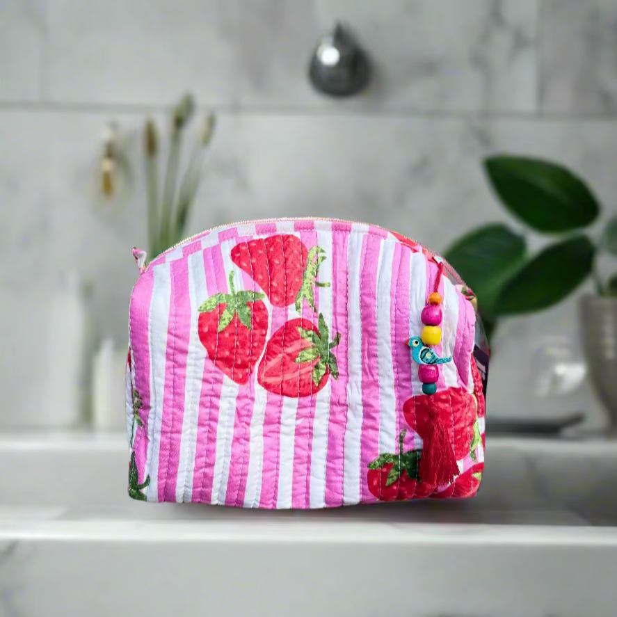 Pink striped pouch with strawberry design on a wooden surface outdoors