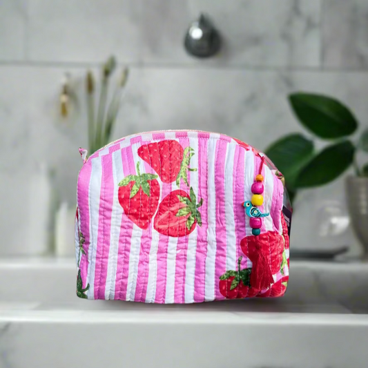 Pink striped pouch with strawberry design on a wooden surface outdoors